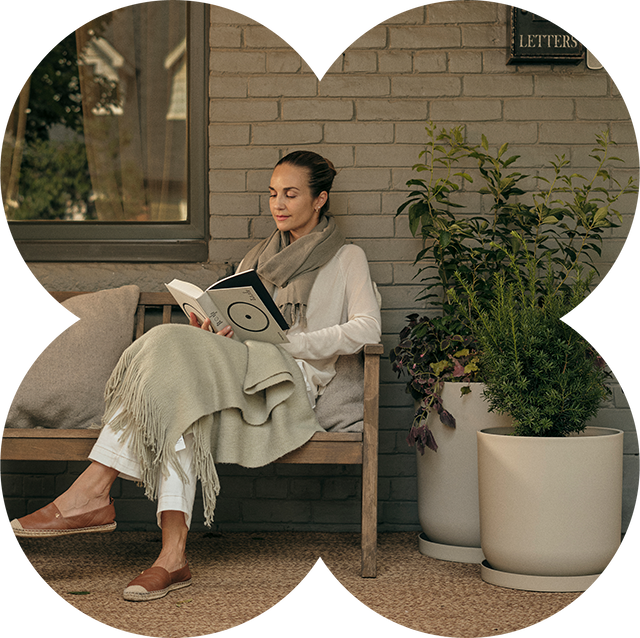 Woman reading a book on a bench next to Mason Kona Planters